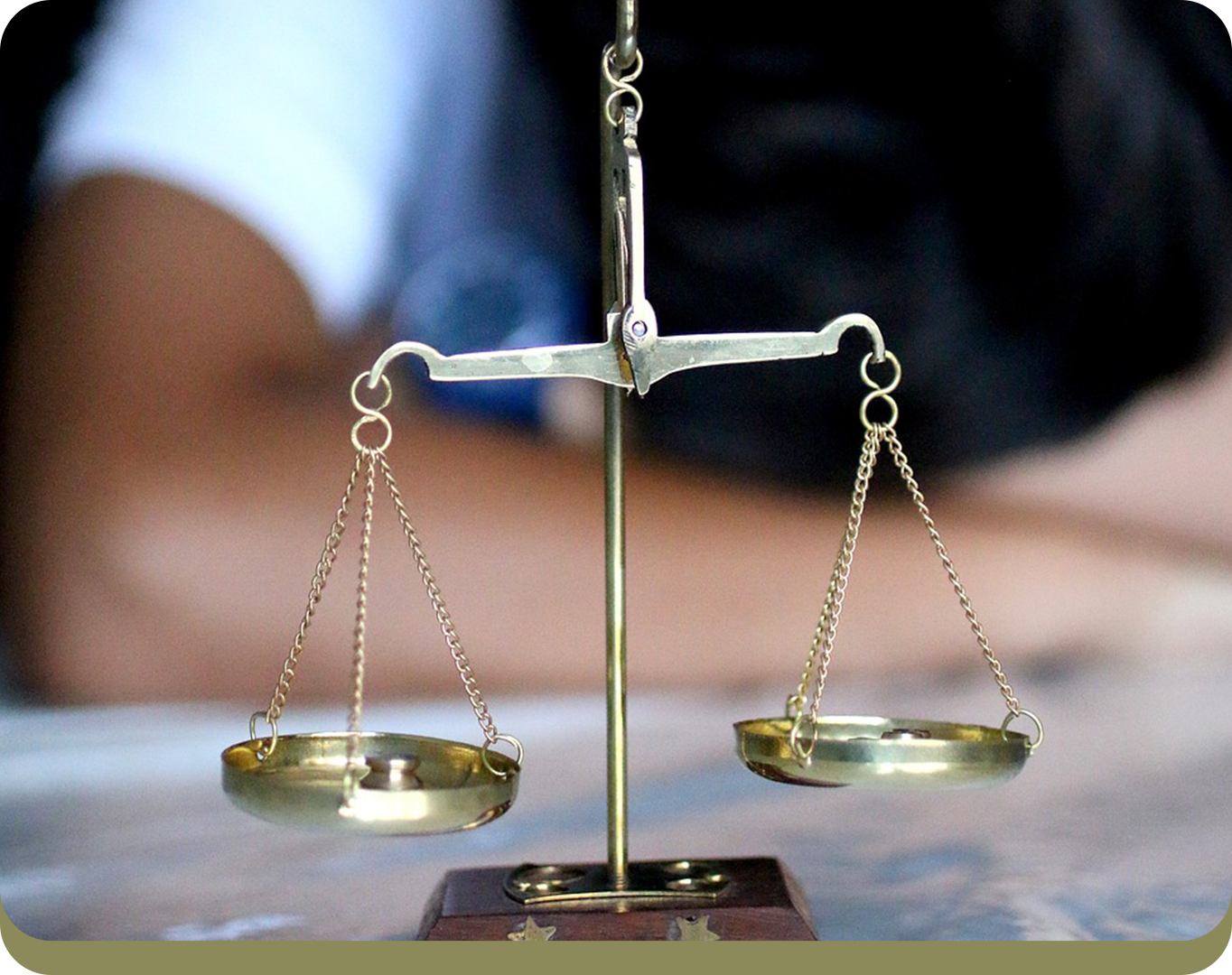 A close-up of a brass balance scale with two empty pans, against a blurred background.